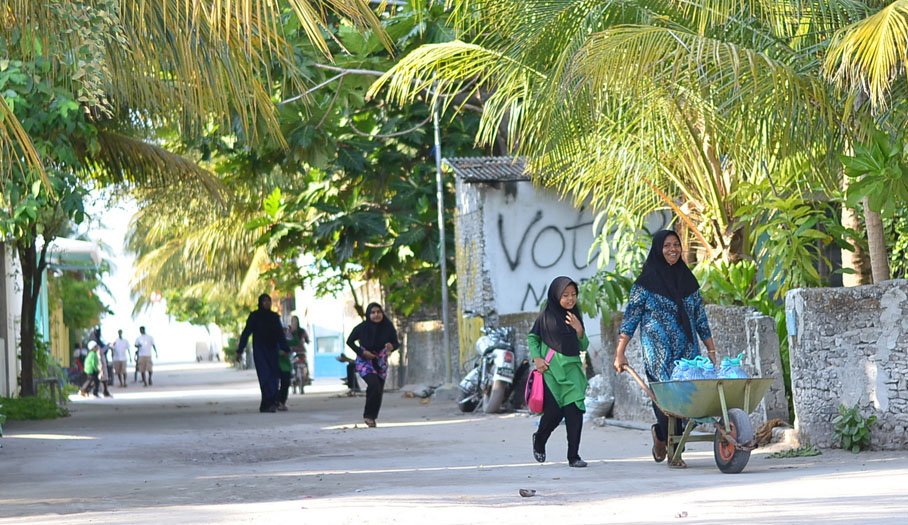 ބ. ކެންދޫ އަންހެނަކު އެއްޗެހިތަކެއް ގެންދަނީ: އެރަށުގެ މަގުތަކުގައި ކޮޕީ ފަތް ގަސް ނޫން އެހެން ގަސްތައް އިންދުންވަނީ މަނާކޮށްފައި -- ހަވީރުފޮޓޯ/ނަސްރުﷲ ސޯލިހު 